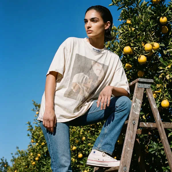 A rejected take: a woman in a Rich But Sad tee with the neck label on the front of the collar